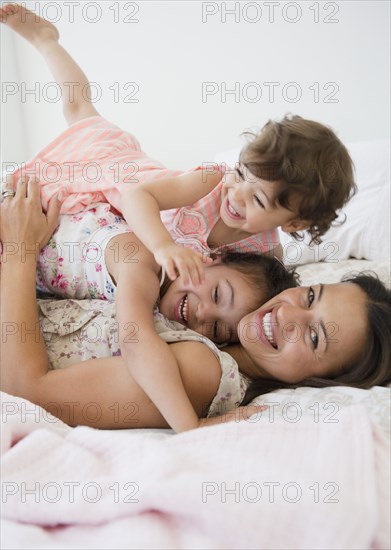 Mother and daughters laying on bed