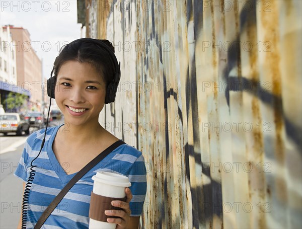 Asian woman listening to headphones and drinking coffee