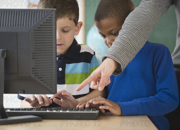 Teacher showing students how to use a computer