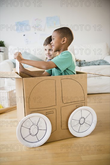 Boys playing in a cardboard car together