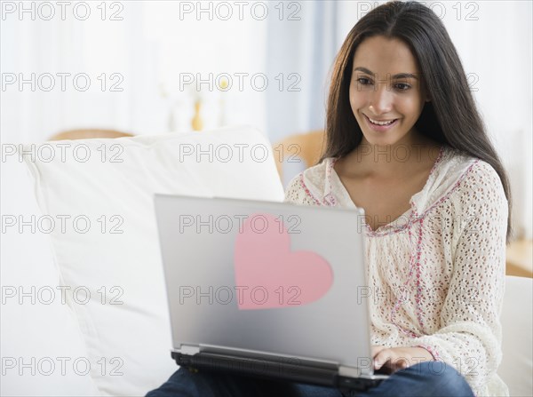 Hispanic teenager using laptop in bedroom