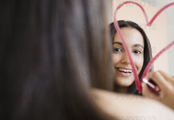 Hispanic teenager drawing heart with lipstick