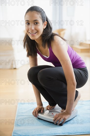 Hispanic teenager weighing herself on scales