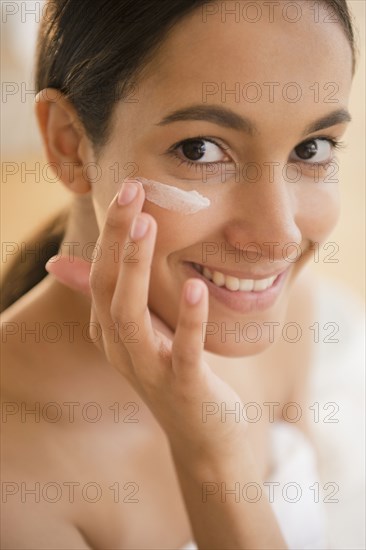 Hispanic teenager putting on face lotion