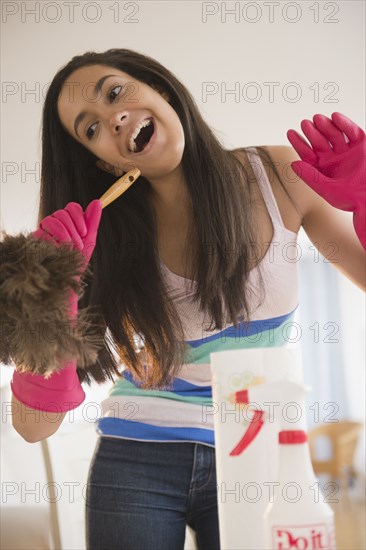 Hispanic teenager singing into a feather duster