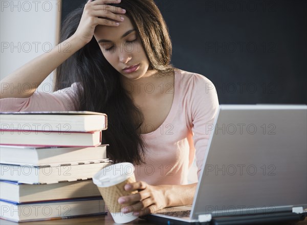 Tired Hispanic teenager holding coffee cup