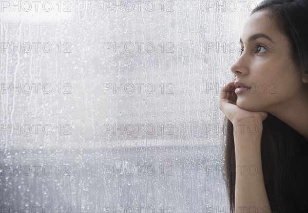 Serious Hispanic teenager looking out window