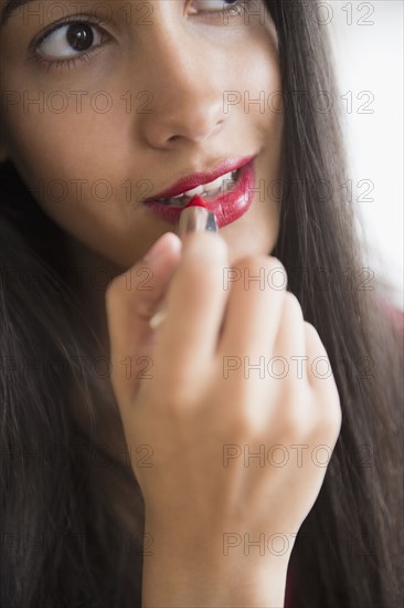 Hispanic teenager putting on lipstick