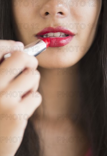 Hispanic teenager putting on lipstick