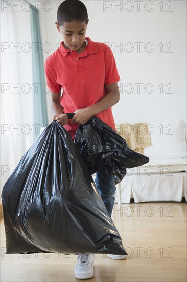 Hispanic boy carrying garbage bag