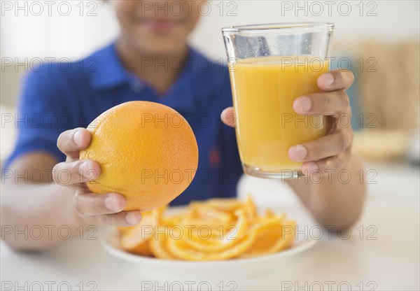 Hispanic boy holding orange and orange juice