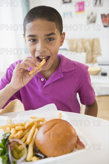 Hispanic boy eating hamburger and french fries