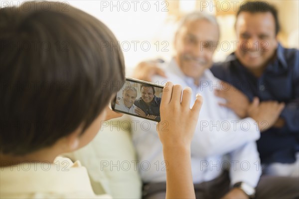 Hispanic boy taking photograph of father and grandfather