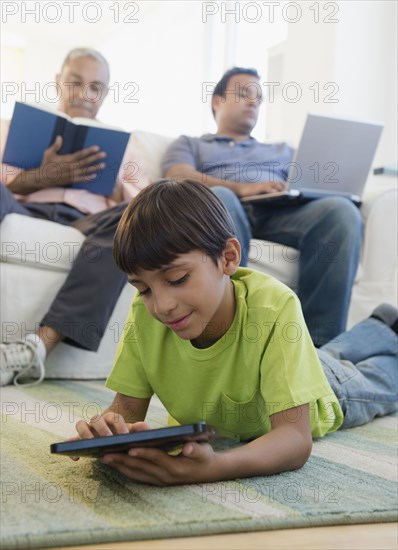 Hispanic boy laying on floor using digital tablet