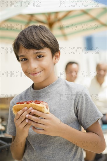 Hispanic boy eating hot dog