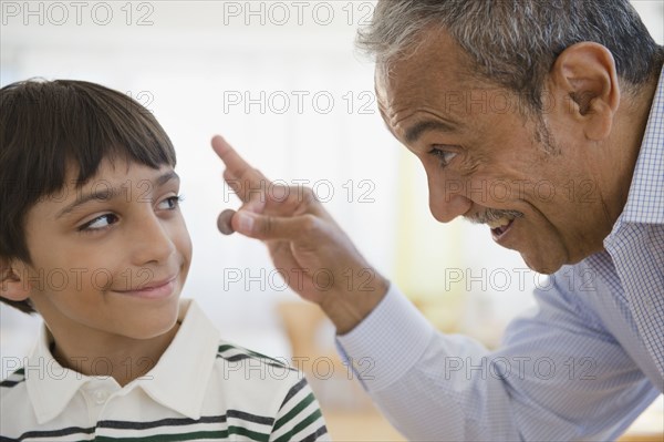 Hispanic grandfather offering coin to grandson