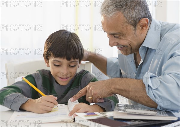 Hispanic grandfather helping grandson with homework