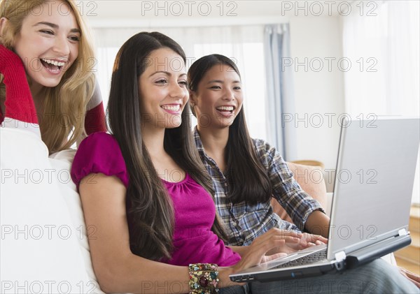 Smiling women using laptop together