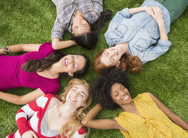 Smiling women laying in grass together