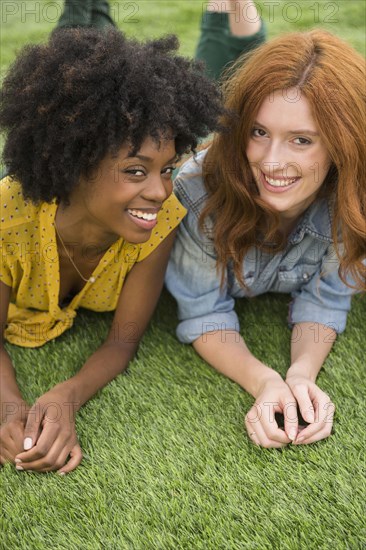 Smiling women laying in grass together