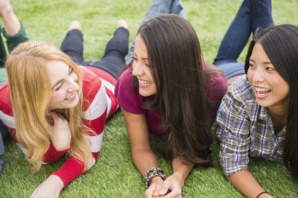 Smiling women laying in grass together