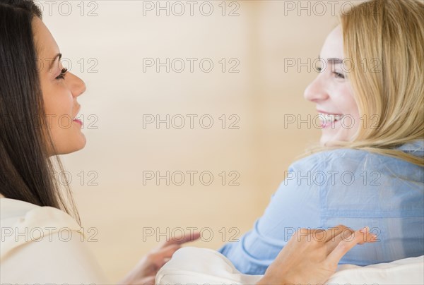 Smiling women talking on sofa