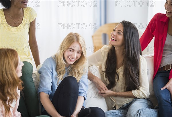Smiling women talking on sofa