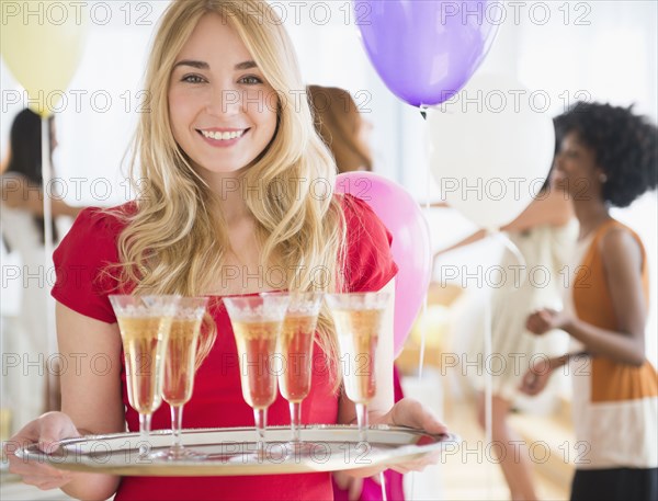 Smiling woman carrying tray of champagne