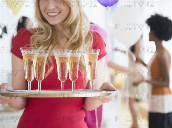 Smiling woman carrying tray of champagne