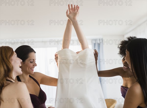 Bridesmaids helping bride into wedding dress