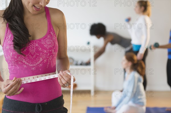 Woman measuring her waist in gym