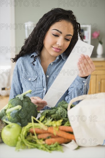 Hispanic woman reading grocery receipt
