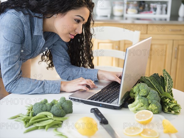 Hispanic woman using laptop to cook