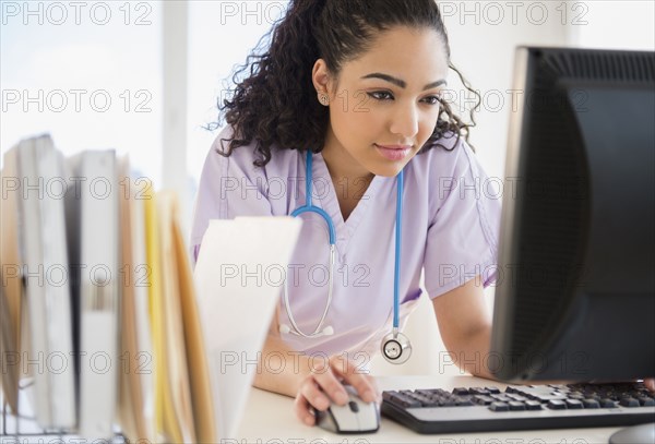 Hispanic nurse using computer in hospital