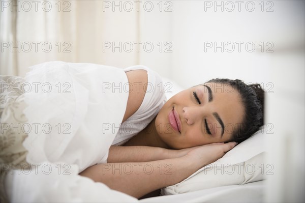 Hispanic woman sleeping in bed