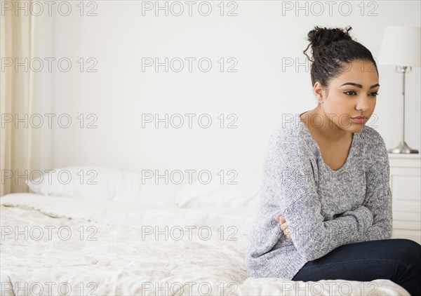 Hispanic woman thinking on bed