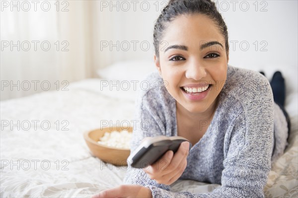Hispanic woman watching television on bed