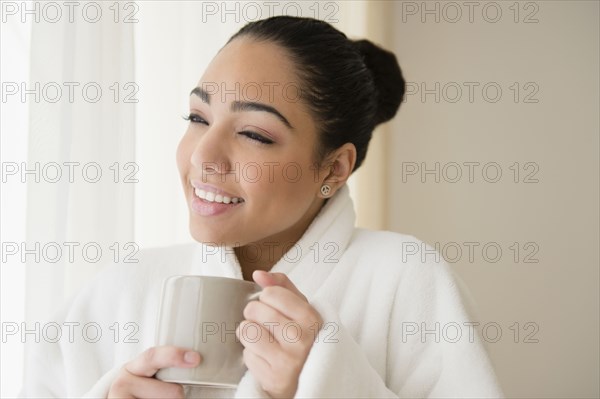 Hispanic woman drinking cup of coffee