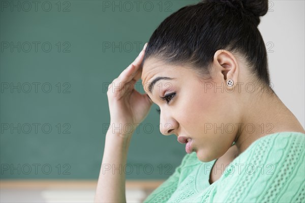 Hispanic woman rubbing forehead