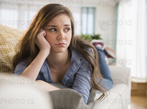 Anxious Hispanic girl laying on sofa