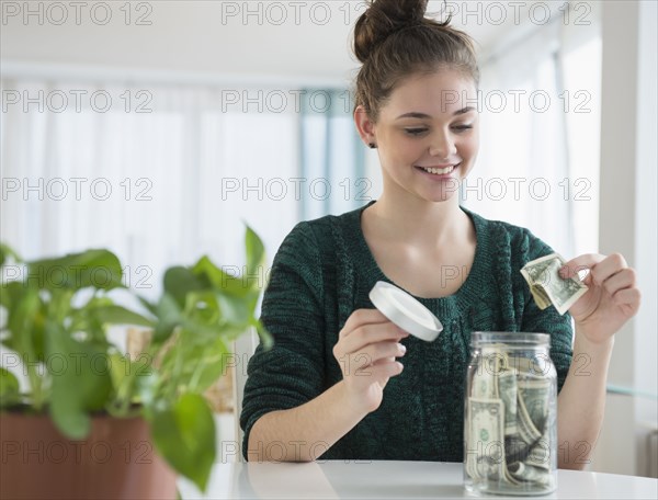 Hispanic girl putting money in savings jar