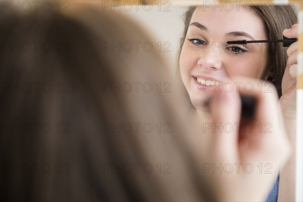 Hispanic girl applying makeup in mirror