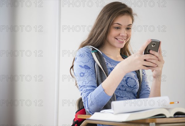 Hispanic girl using cell phone at desk