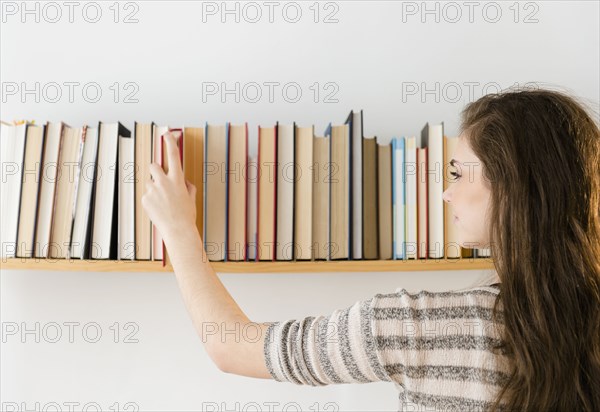 Hispanic girl selecting book from shelf