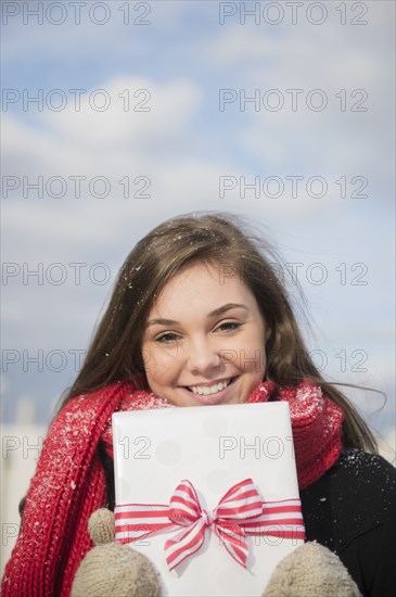 Hispanic girl holding present in snow