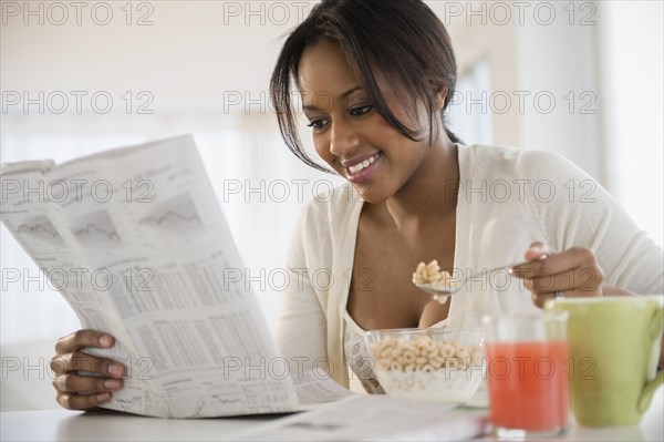 African American woman reading newspaper at breakfast