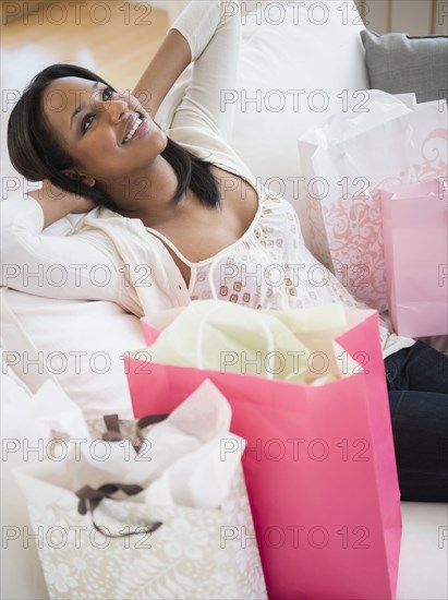 African American woman with shopping bags on sofa