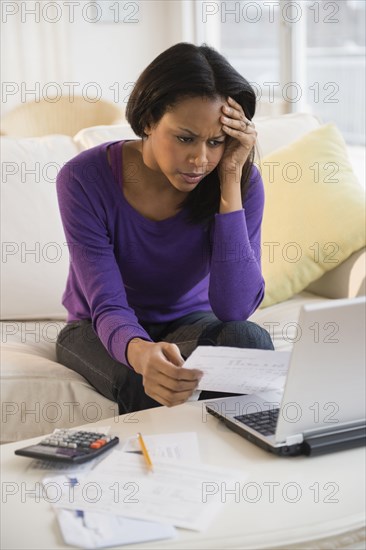 African American woman paying bills with laptop