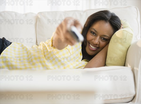 African American woman watching television on sofa