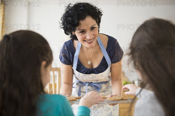 Mother giving daughters fresh baked cookies